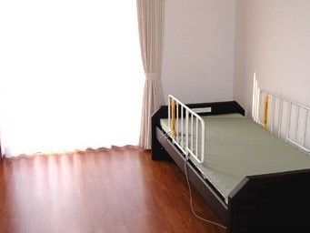 施設内の居室に小さなベッドが置いてある様子。大きな窓から日差しが差し込んでいるのがわかる