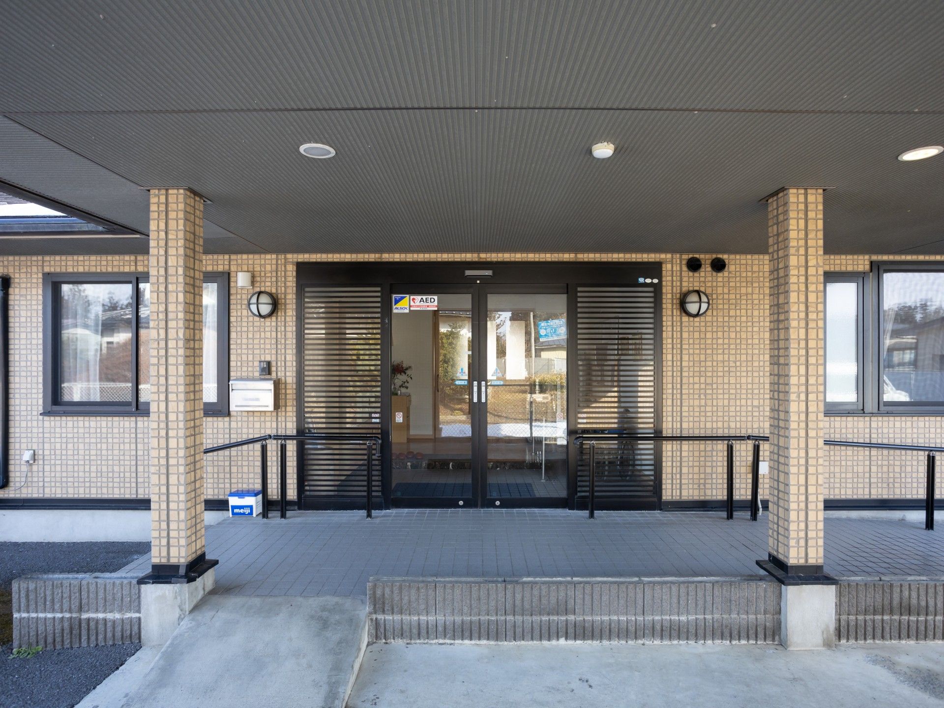 手を取り合って微笑んでいるエプロンを付けた若い女性スタッフとカーディガンを着た車いすの高齢女性。