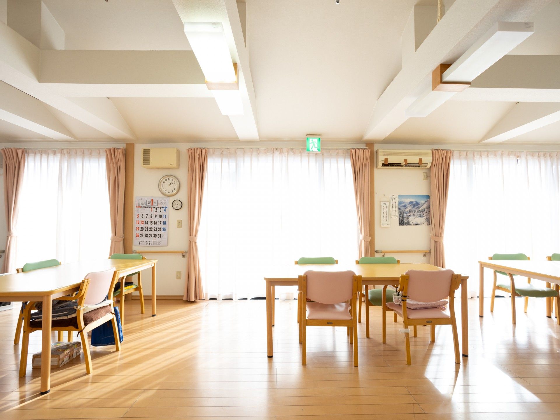 フラワーアレンジメントを楽しんでいる眼鏡をかけた高齢男性。エプロンを付けた女性スタッフが手伝っている。