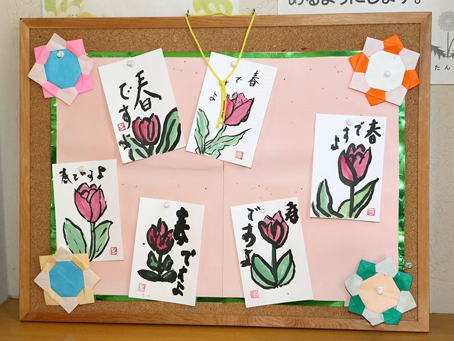 高齢者がレクリエーションで書いたものを飾り付けてある様子。施設内の廊下の場面