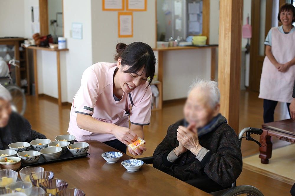 笑顔で食事を手伝うスタッフ