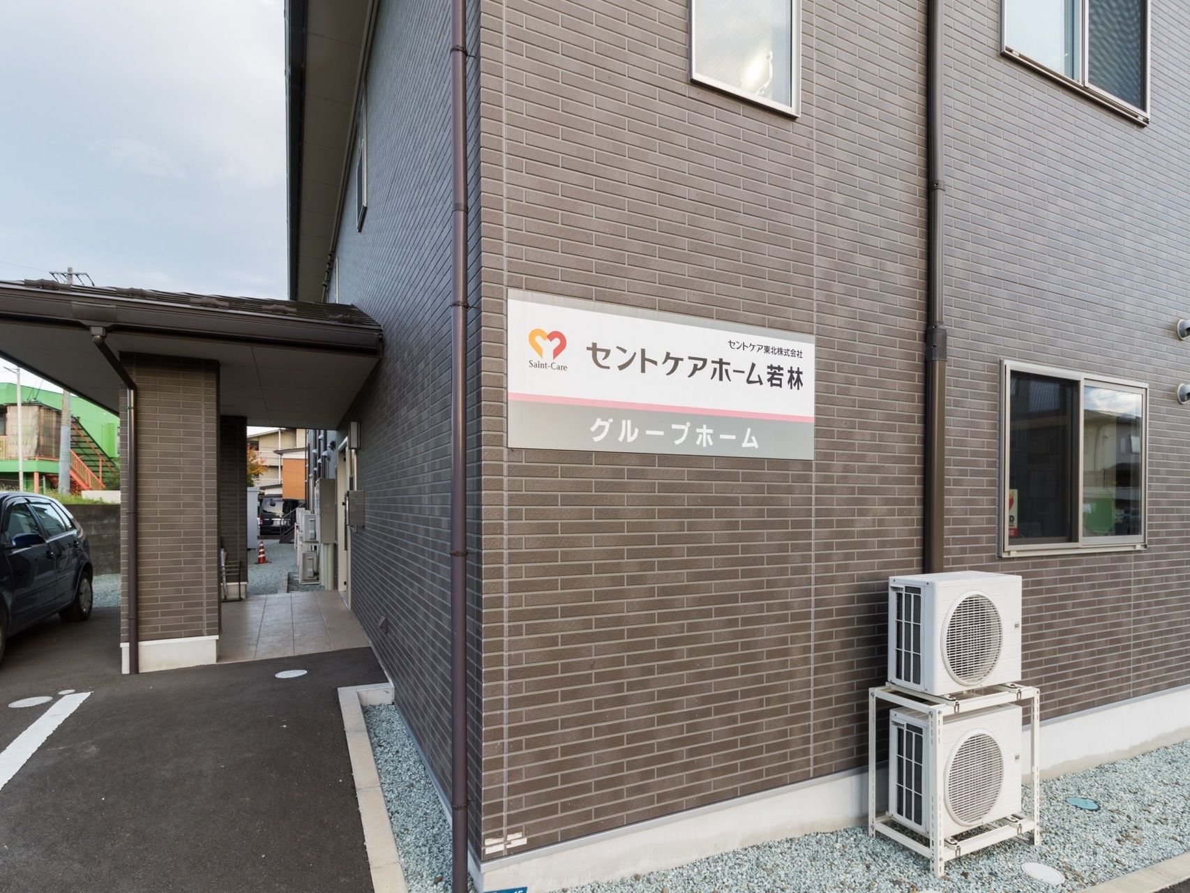 建物横側の壁に施設名の入った看板が取りつけられている。建物に馴染む色合いで、遠くからも見やすい文字表記がされている。