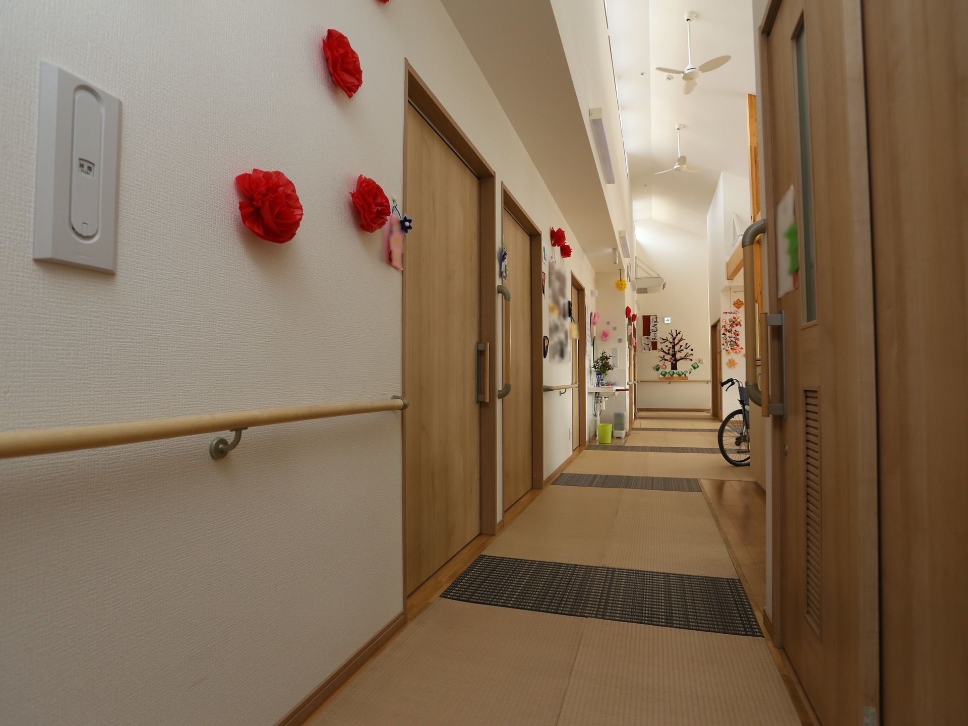 奥に向かって廊下が伸びており、天井には扇風機が取り付けられている。両側の壁に引き戸が並び、壁に飾り付けがされている。