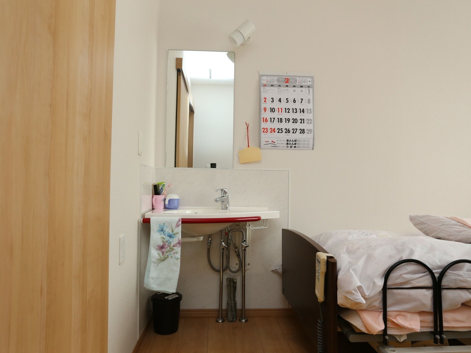 居室に設置された洗面台の画像である。中央に洗面台があり、流しの縁にタオル掛けが取り付けられ、花柄のタオルがある。