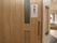 トイレへ続く引き戸扉である。ドアいは白い紙でひらがなでべんじょと書かれて貼られている。ドアの横の壁に手すりがある。