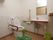 個室トイレの画像である。中央に洋式トイレがあり、床に緑色のトイレマットが敷かれている。右側の壁に洗面台と鏡がある。