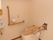 個室の中央に温水洗浄便座が取り付けられた洋式トイレがある。便座の手前には折り畳み式の手すりがある。