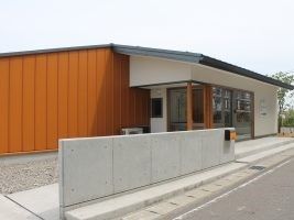 モダンなデザインの平屋建て建物。フラットな壁と屋根、エントランスにはスロープらしきものがある