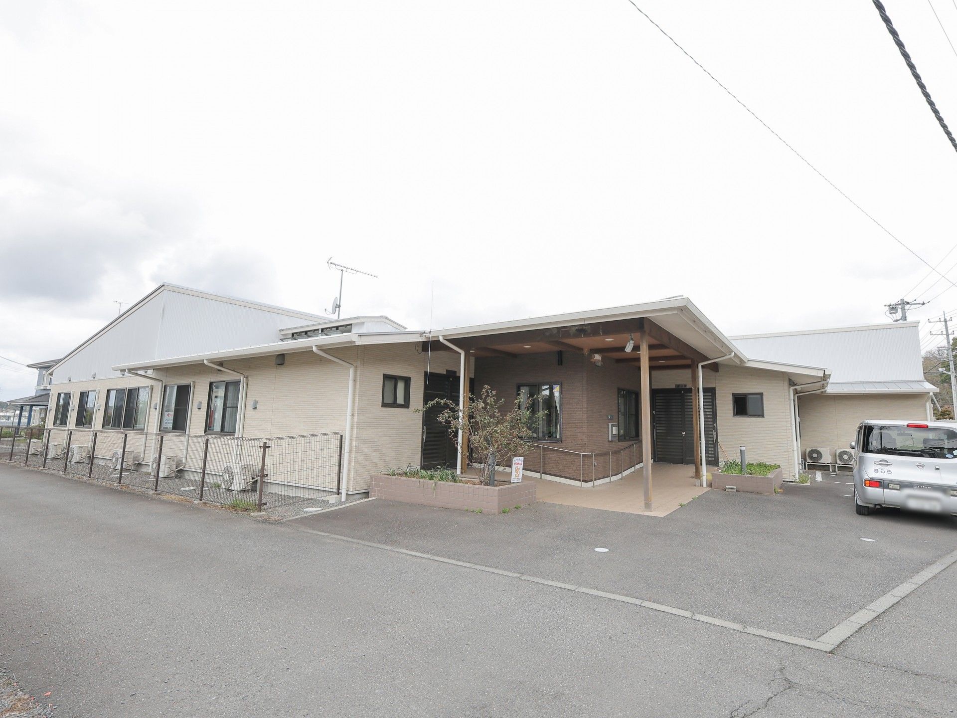 玄関に手すりが付いた平屋建ての建物。花壇も多く設置され、段差はない。