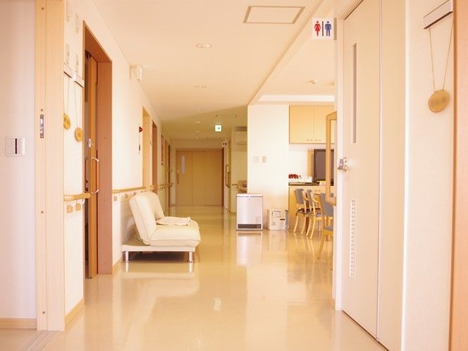 施設内の廊下を写した写真。大きなソファやいす、机、両側に個室のドア