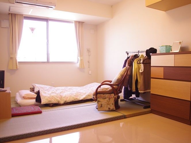 畳とふとん類が置いてあるスペースとおしゃれなタンス、洋服掛けがある部屋