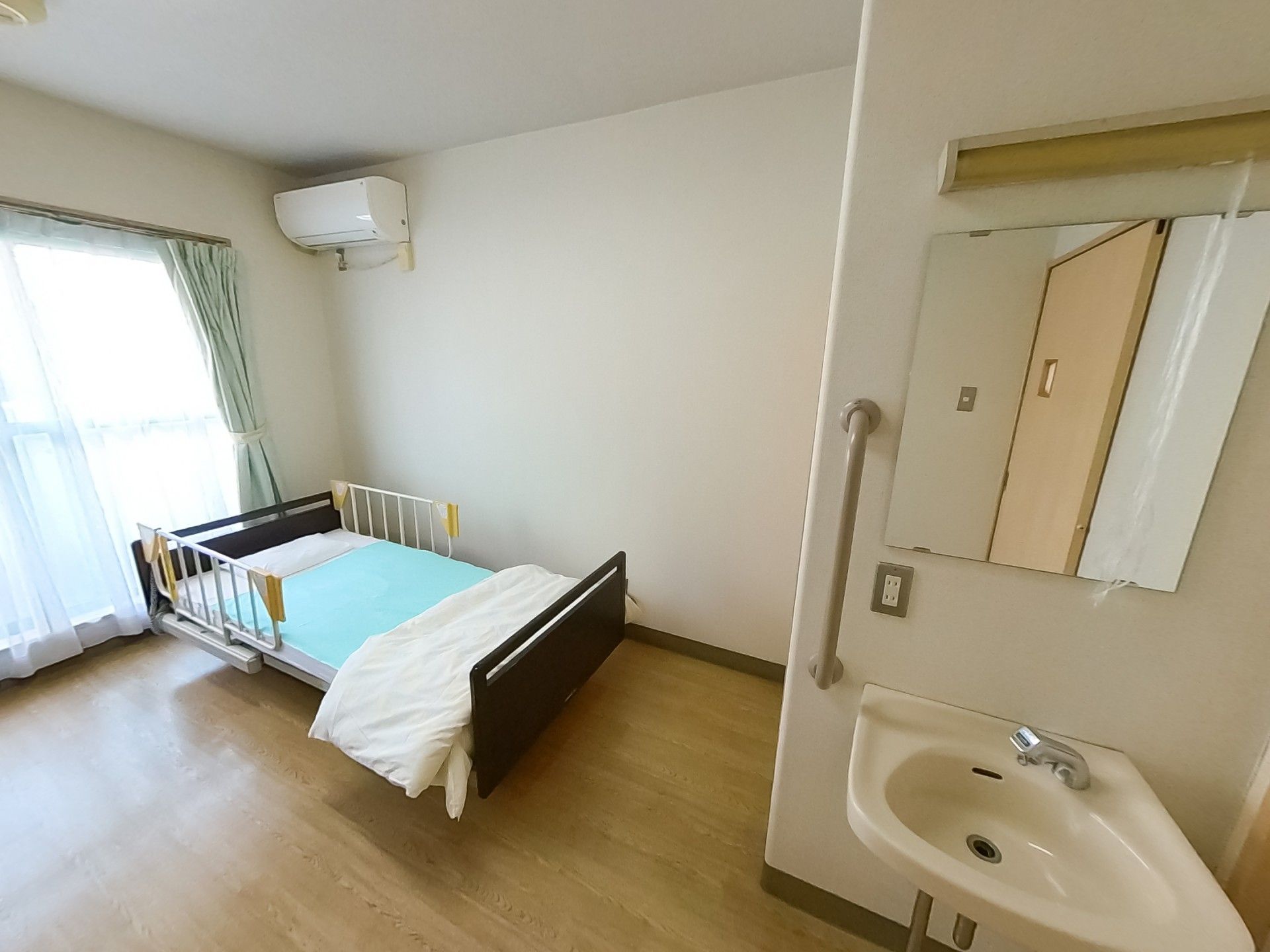 明るい個室のベッドと洗面台