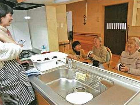施設のキッチンでスタッフと会話を交わしながら作業している高齢者の様子