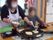 ホットプレートでお好み焼きを焼いている女性スタッフとそれを見ている高齢女性。
