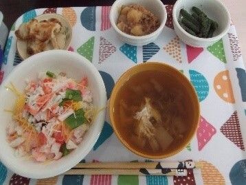 カラフルなトレーの上にはちらし寿司や汁物、野菜の和え物、肉のソテーなどが置かれている。