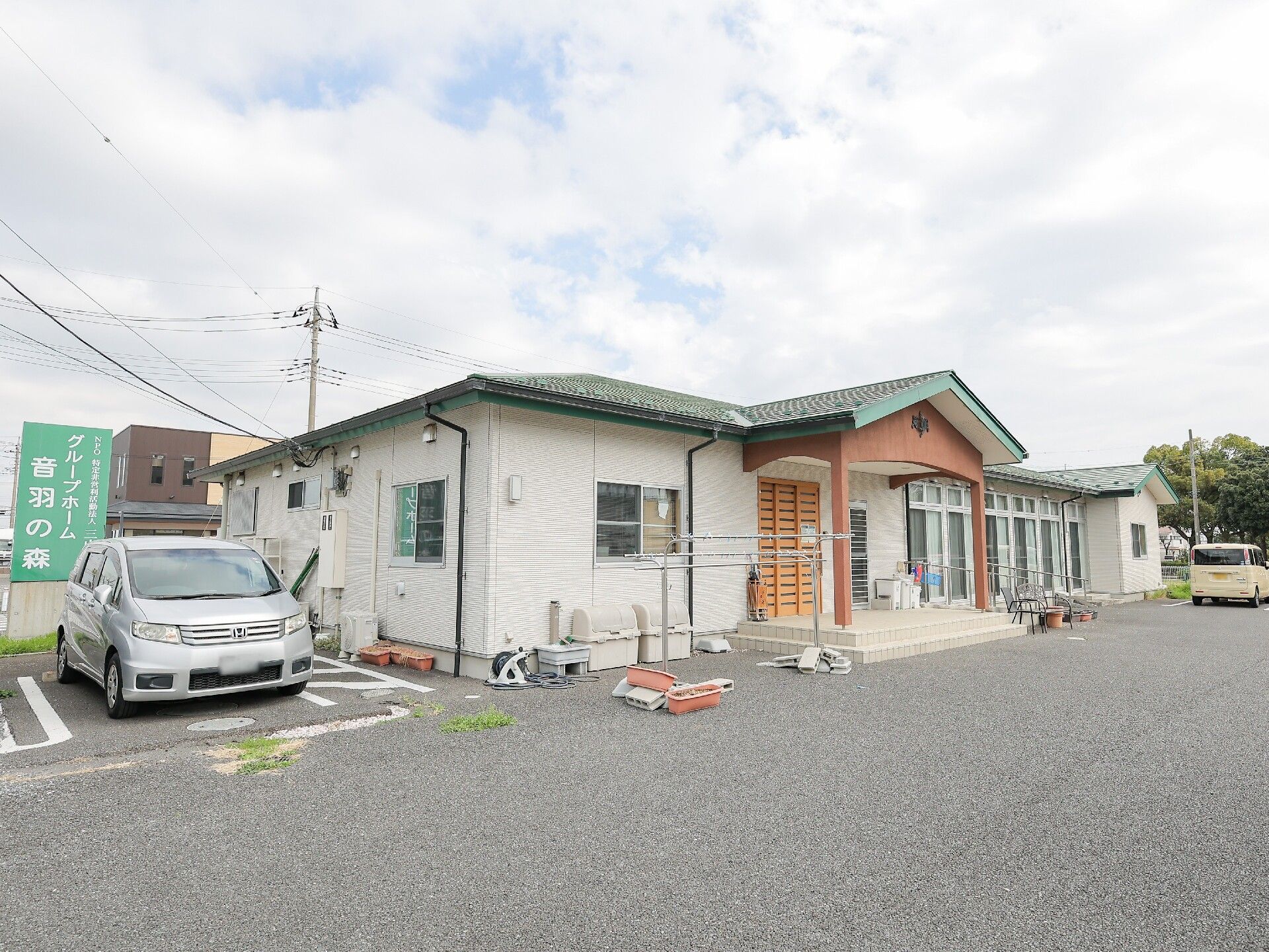 広い駐車場も完備されている平屋建ての建物のホーム。建物の横には車が止まっている。
