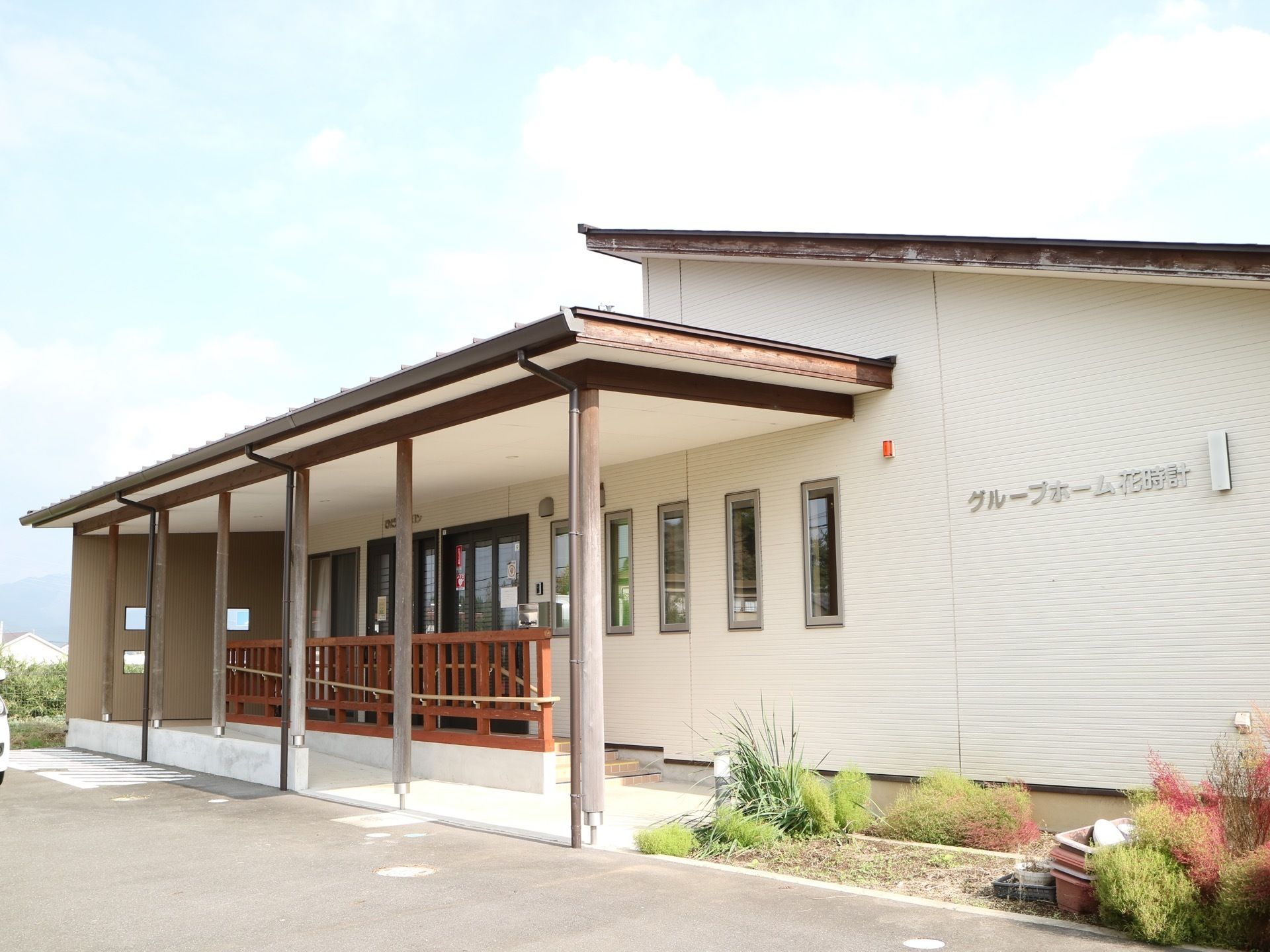 施設は外壁が白い１階建ての建物で、三角の屋根が付いている。玄関の上には大きなひさしがあり、横には花壇が設けられている。