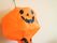 ハロウィンのかぼちゃの形をしたインテリアが壁に吊るされている。全体はオレンジ色で、顔のパーツは黒で描かれている。