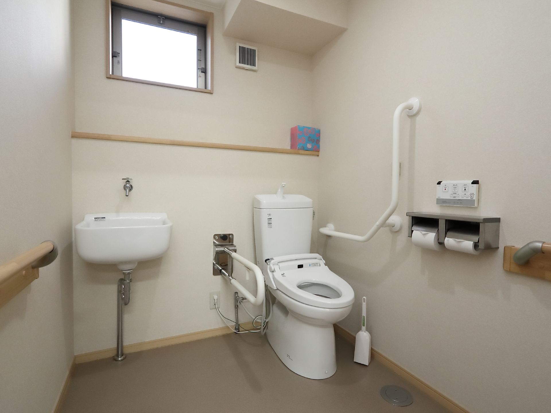 共用トイレは広いつくりになっており、車椅子のままで使いやすいタイプとなっている。温水洗浄の操作パネルは左手側にある。