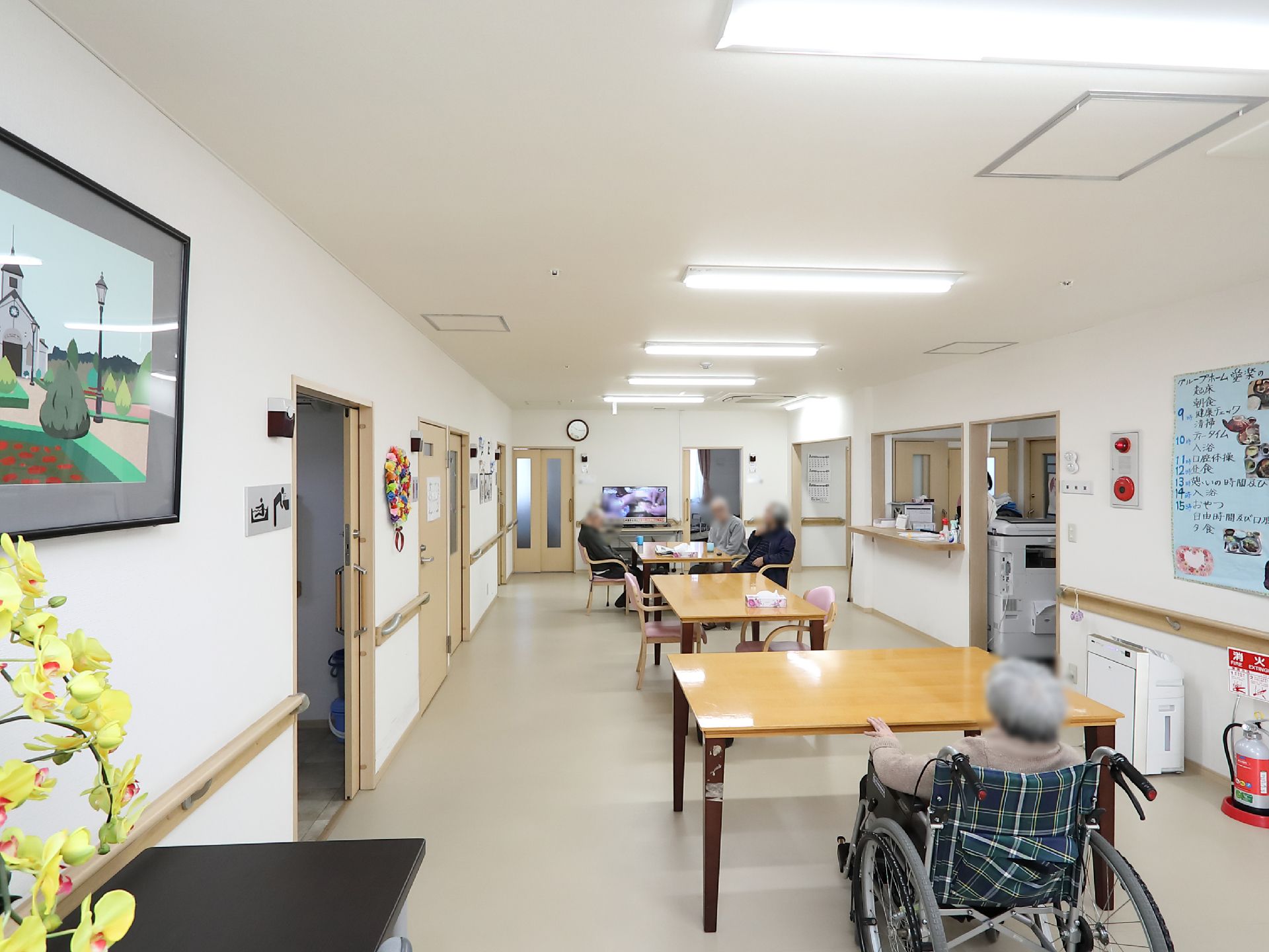 縦方向に、複数の木製テーブルが配置されている。壁側に手すりが取りつけられ、火災報知機や消火器も設置されている。