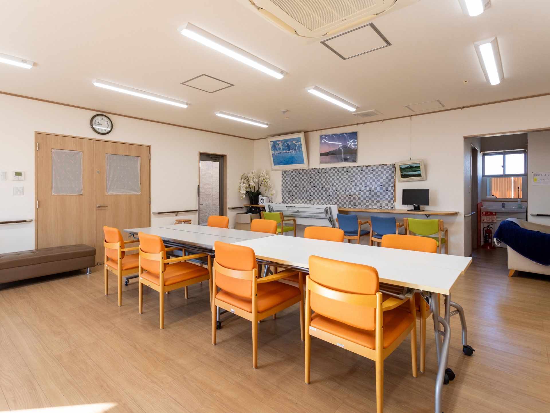 笑顔でこちらを向いている施設のスタッフと車いすに乗っている高齢者の様子。施設で写された写真