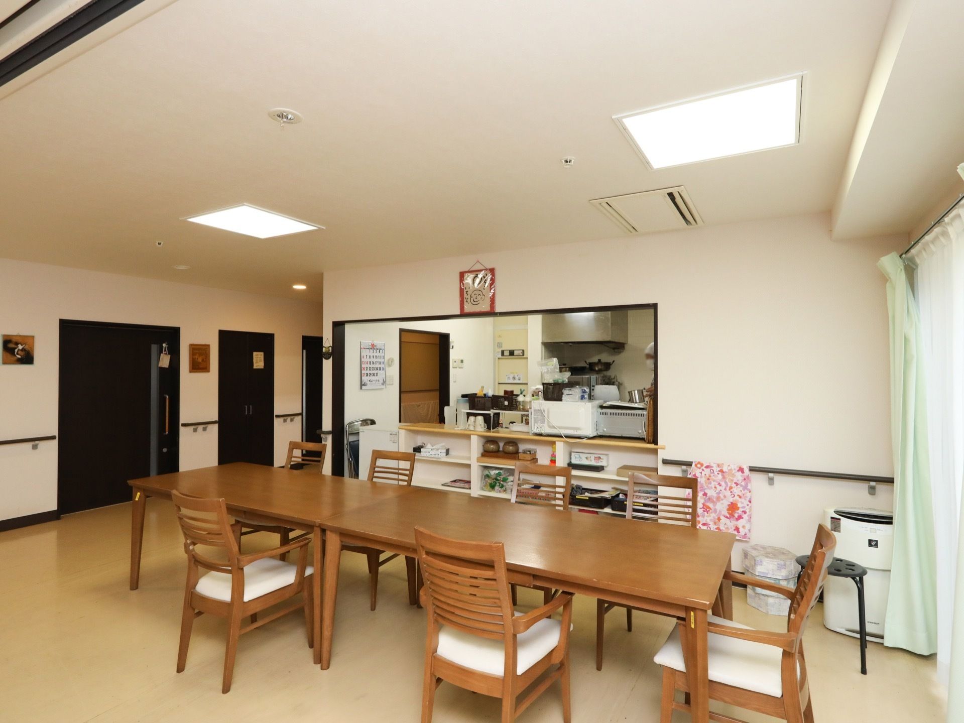 食堂には茶色いダイニングテーブルが設置されており、椅子が間隔を空けて並べられている。窓の側には空気清浄機が置かれている。