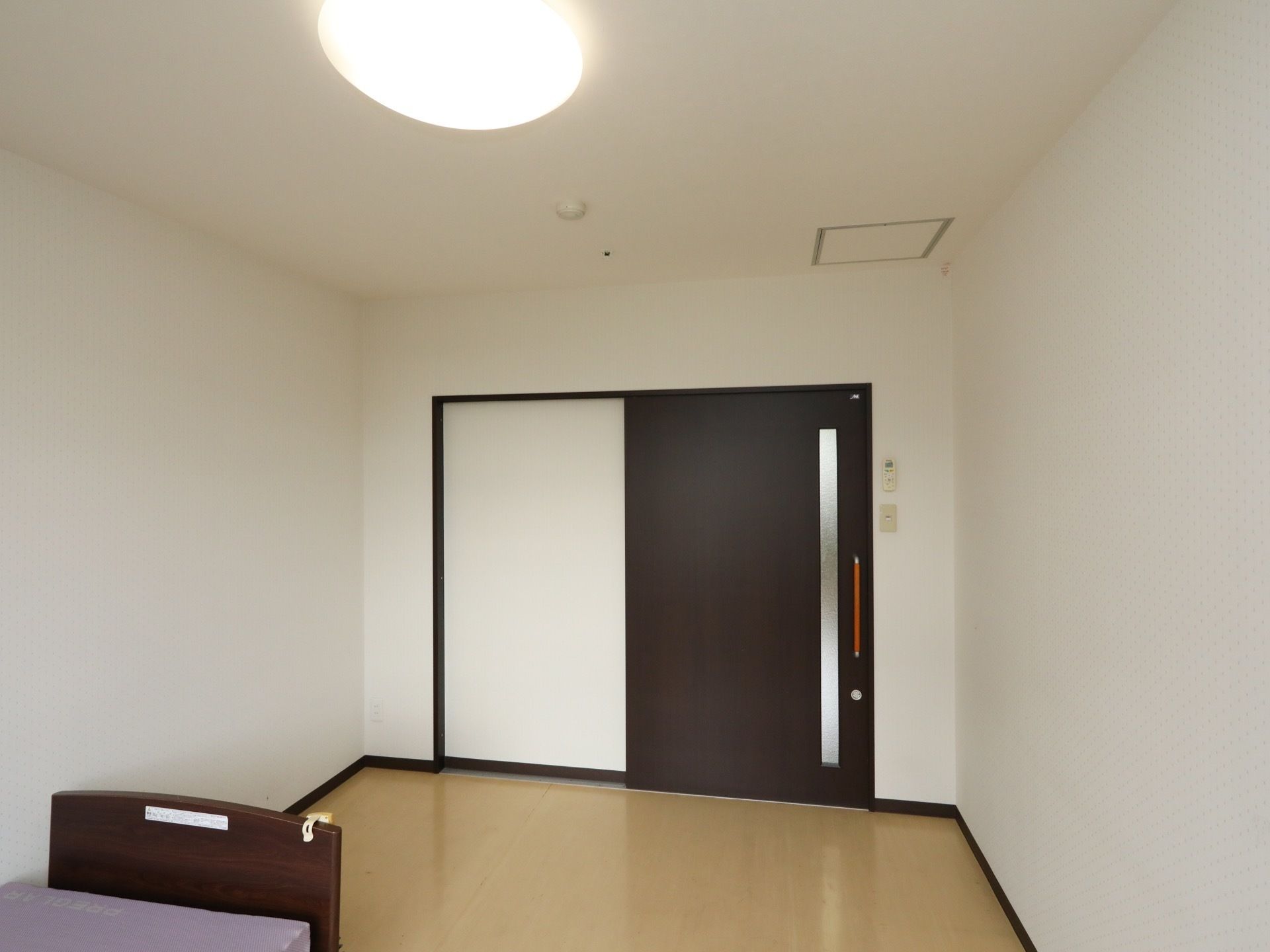 居室のドアは大きな引き戸になっていて、車椅子でも出入りできる十分な広さがある。天井にはシーリングライトや火災報知器などが設備されている。