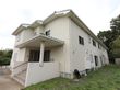 施設は白い建物。玄関の前には階段があり手すりも設置されている。建物の後ろには木がたくさんあり、緑の多い環境である。