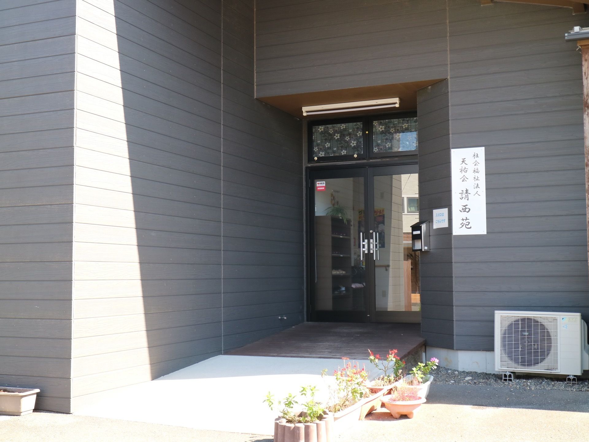 入口の横には表札が掲げられている。勾配の小さなゆるやかな通路が続いており、どなたでもスムーズに入館できる。