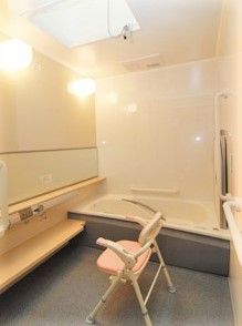 シャワーチェアが付いている高齢者用の浴室。壁型にL字型の手すりがある