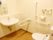 エル字型の手すりと呼び出しボタンが設置されたトイレ。シャワー付きのモダンなデザイン。