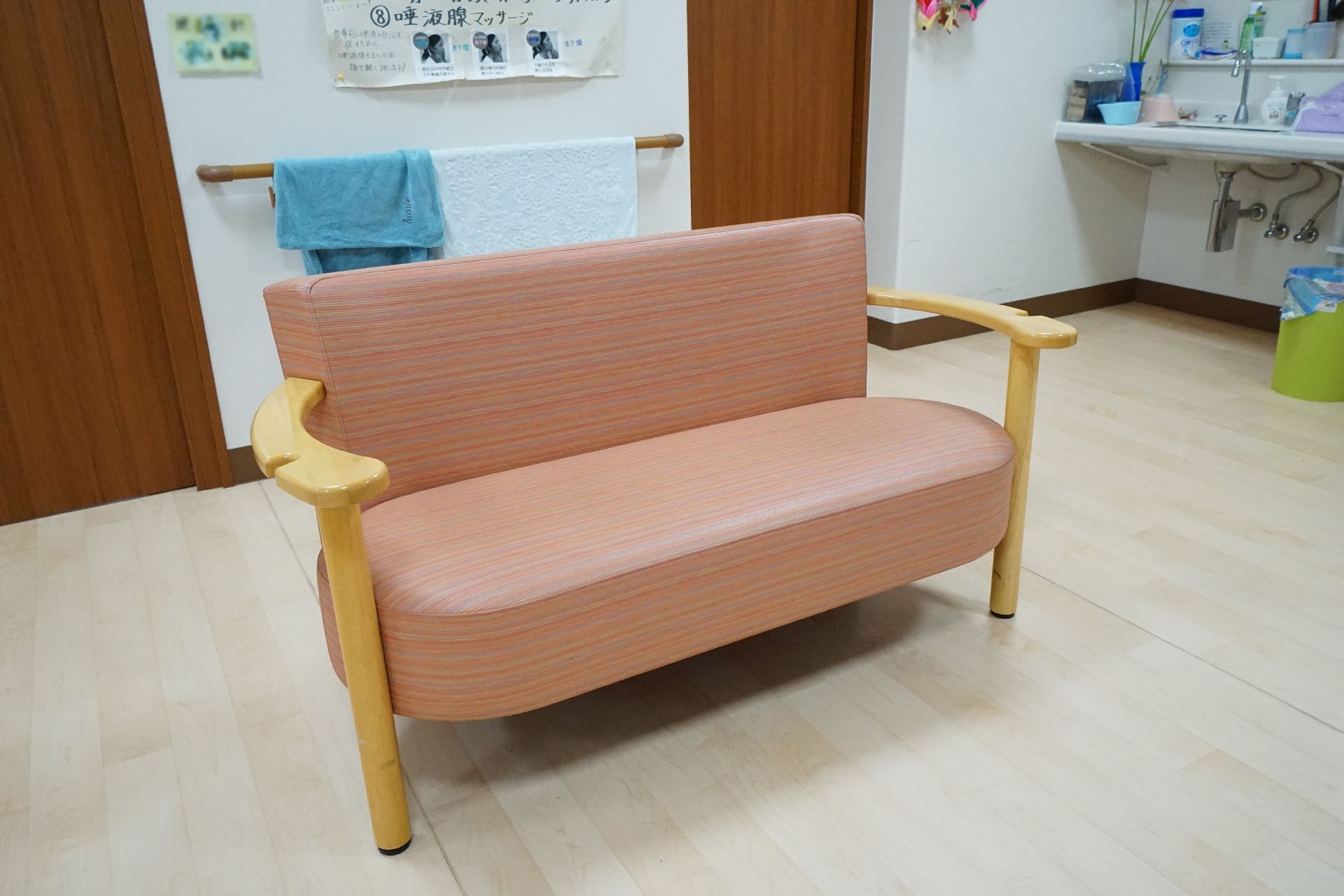 自然豊かな場所を車いすで散歩している高齢男性とそれを補助しながら話している女性スタッフ