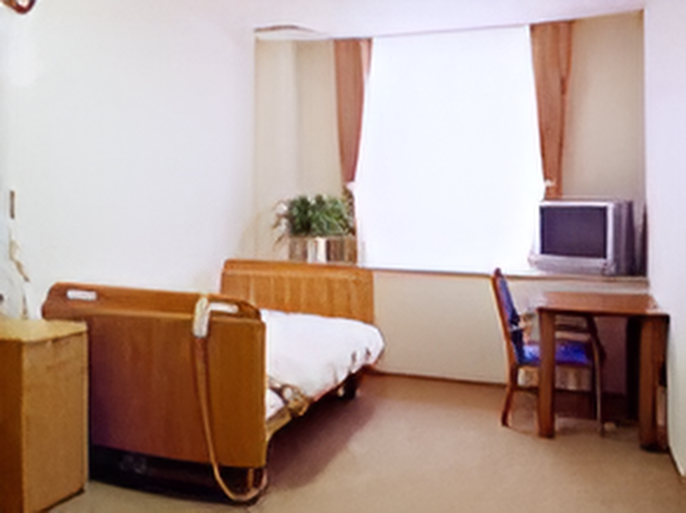 寝具付きのベッドやテレビ、デスクセットなどが置かれている部屋にはカーテンが付いた大きな窓がある。