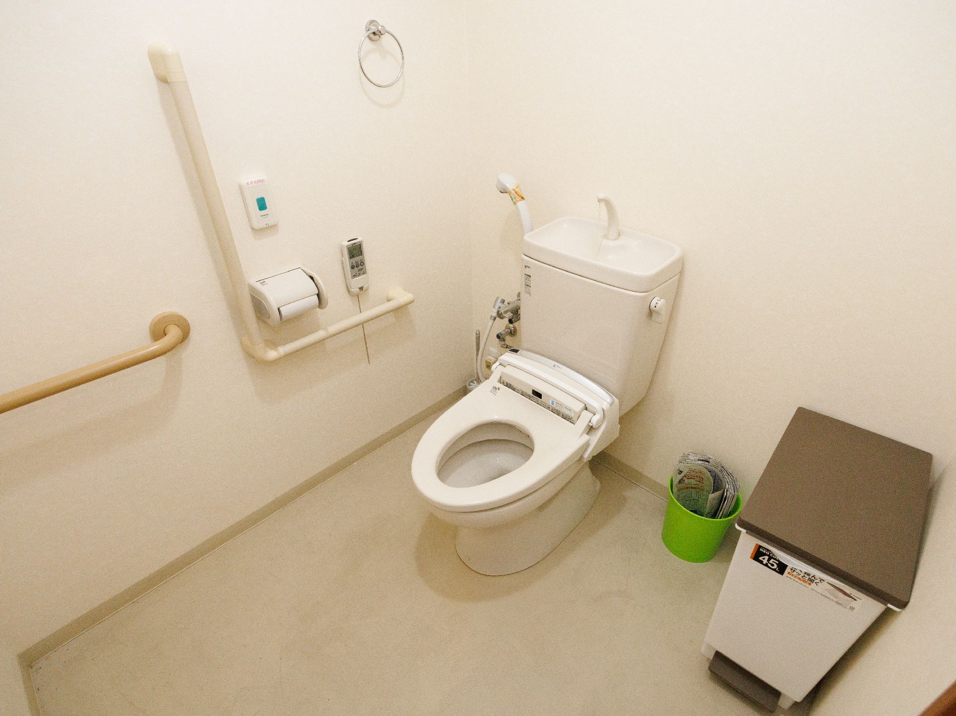 車いすの高齢女性とエプロンを付けた若い女性スタッフが日当たりのいい屋外で散歩を楽しんでいる。