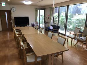 テレビやソファ、ダイニングテーブルセットが複数置かれた食堂には大きな窓があり、庭が見える。