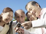 デジカメの画像を見ながら微笑んでいる男女。楽しそうに笑っている高齢者のグループ