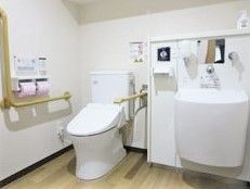 洗い場の付いたトイレは広く、エル字型の手すりや可動式の手すりが付いている。