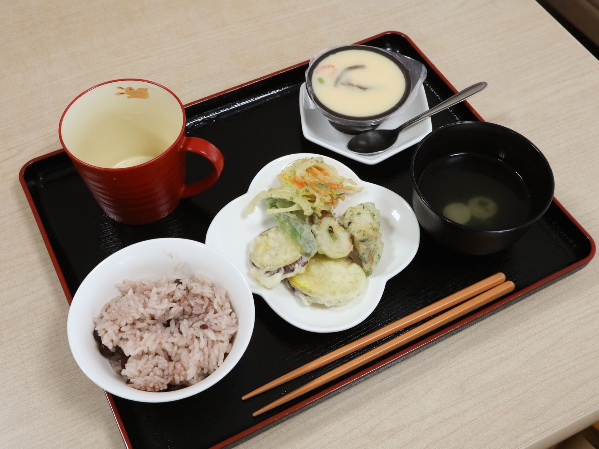 主菜の皿には、かき揚げや芋やちくわなどの天ぷらが盛り付けられている。赤飯、お吸い物、茶碗蒸しもついて、栄養バランスが考えられた献立である。