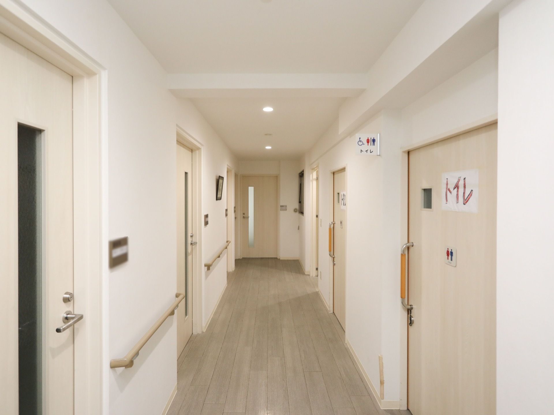 天井、壁、床、ドアなどが白系統で統一されている。トイレのドアはスライド式で、大きくトイレと書かれた紙が貼られている。