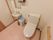 広くスペースを確保したトイレには、洗面台や鏡、ペーパーホルダーが設置されており、便器そばには清掃用具が置かれている。