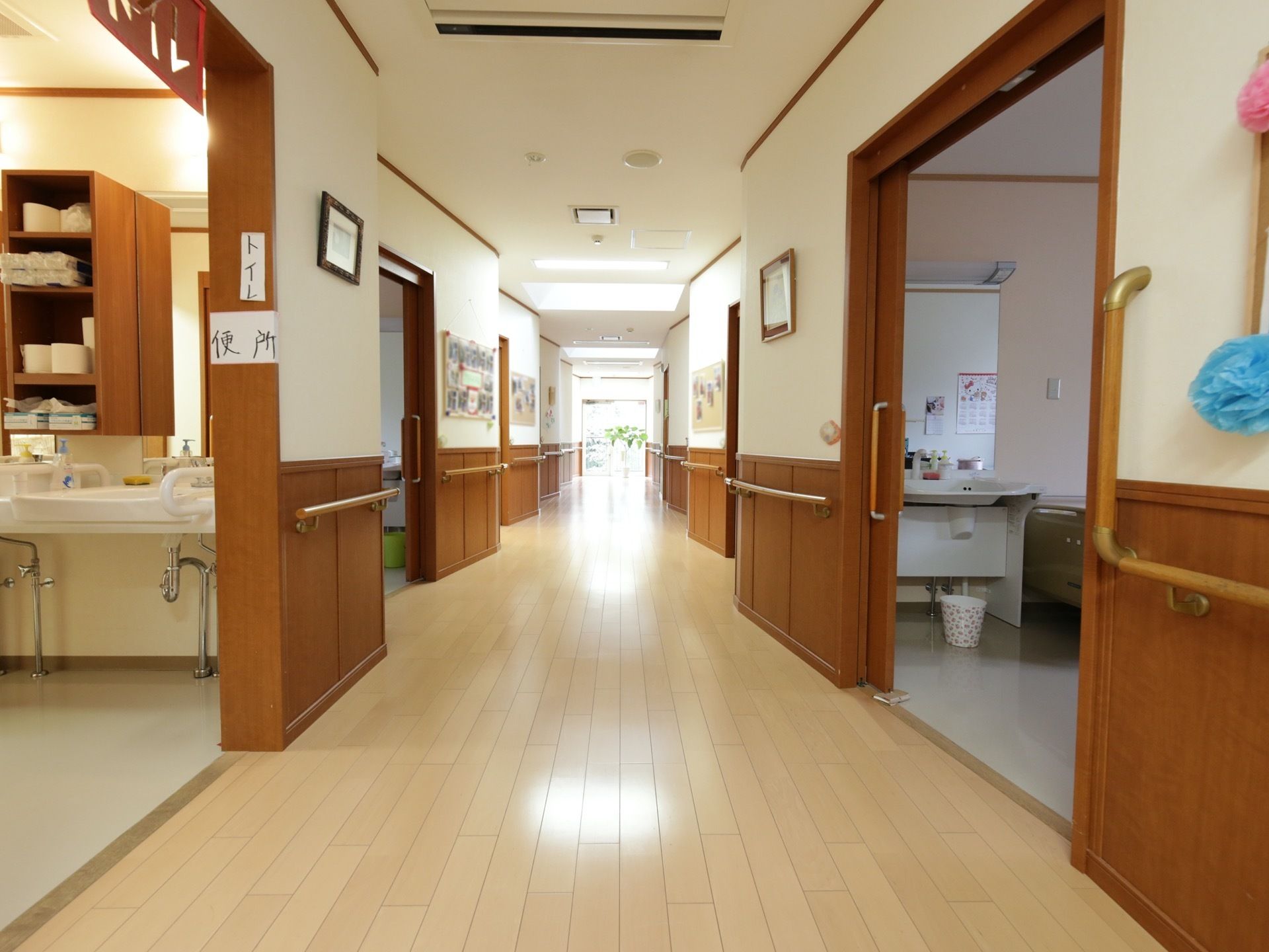 手すりの取り付けられた広い廊下である。手洗い場には、トイレや便所などがわかりやすいよう張り紙がしてある。