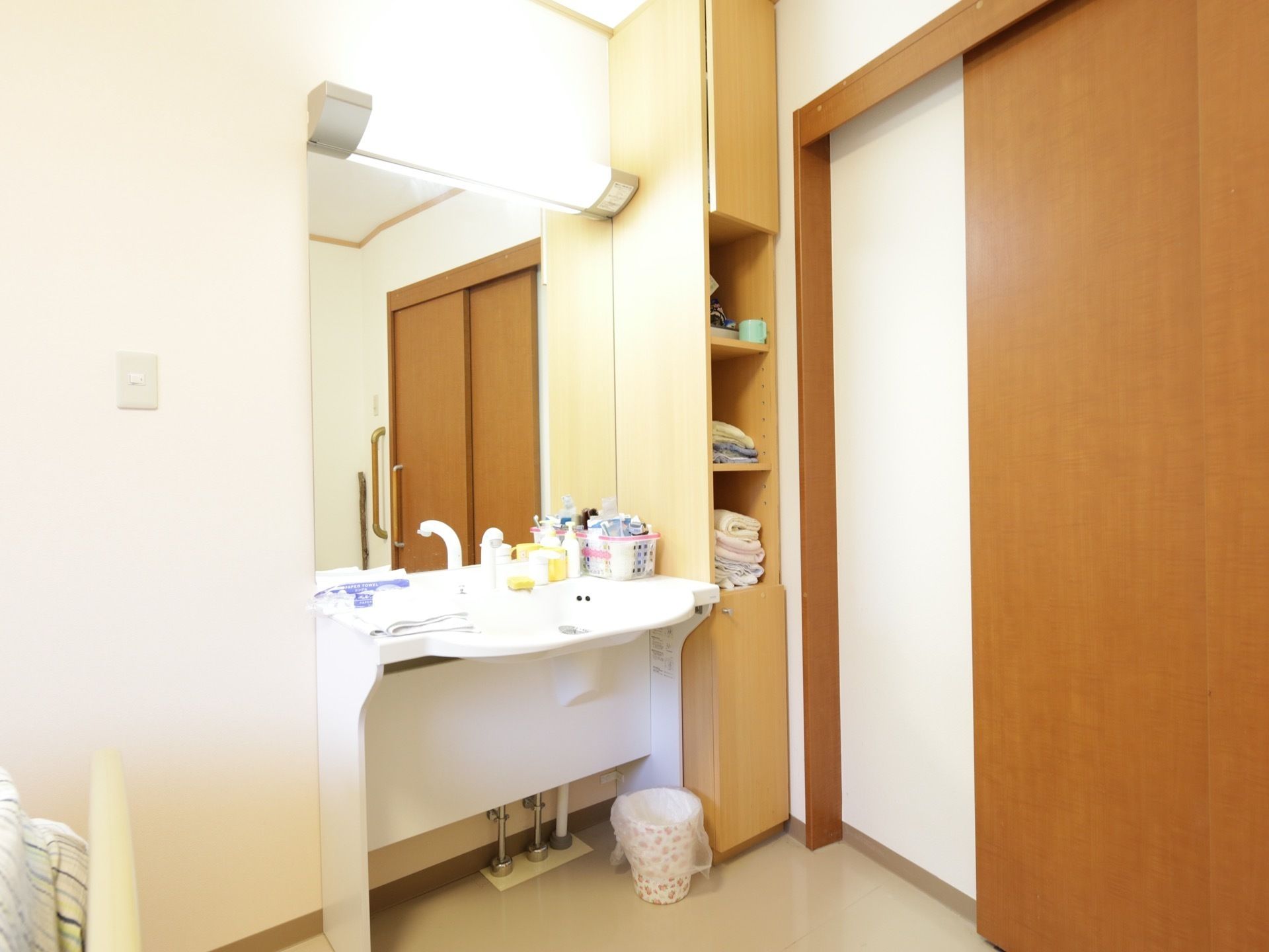 収納の充実したきれいな洗面台である。すぐそばに棚が設置されているので、タオルなどの出し入れがしやすい。