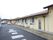 施設は平屋建てで横に長い。窓の外側に照明があり、エアコンの室外機が並んでいる。窓は上下連窓になっている。