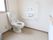 白い壁を採用した清潔感あるトイレである。快適に使用できる温水洗浄便座器が完備され、ゆとりあるスペースを確保している。