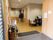 施設の玄関は、段差のない空間が広がっている。ベンチの上に消毒スプレーがのっている。飾り棚があり、パンフレットなどがラックに収められている。