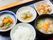 黒いトレーの上に食事が乗せられている。手前にご飯と味噌汁が置かれ、奥におかずが３品、それぞれ違う皿に盛り付けられている。