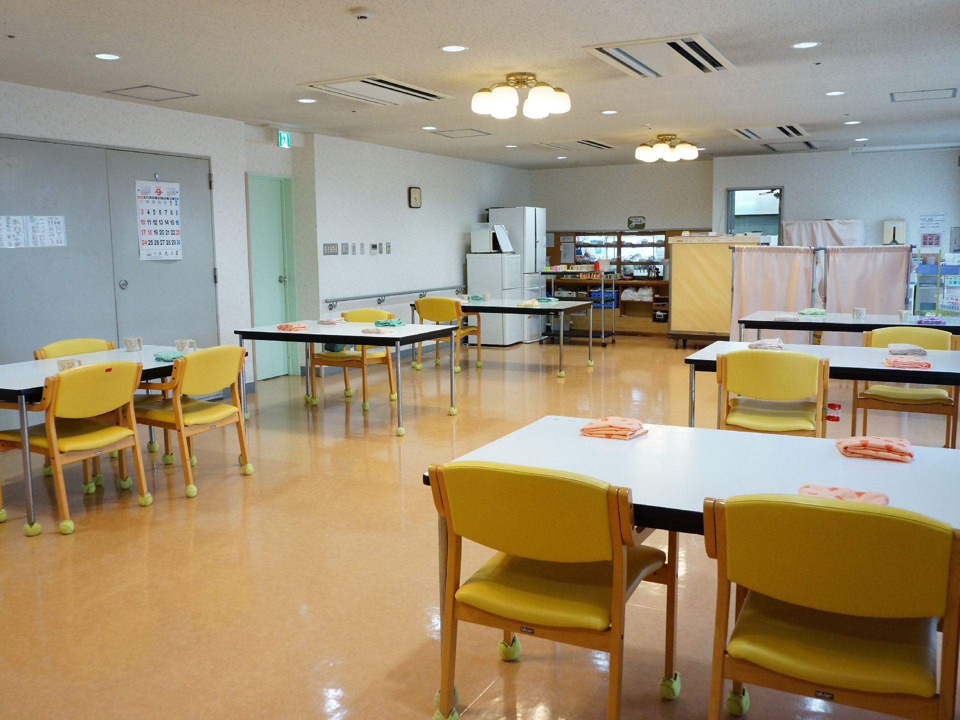 食堂の様子。複数のテーブルが置かれ、1から3脚の椅子が備え付けてある。車いすなどを利用したまま座ることのできるスペースも設けられている。