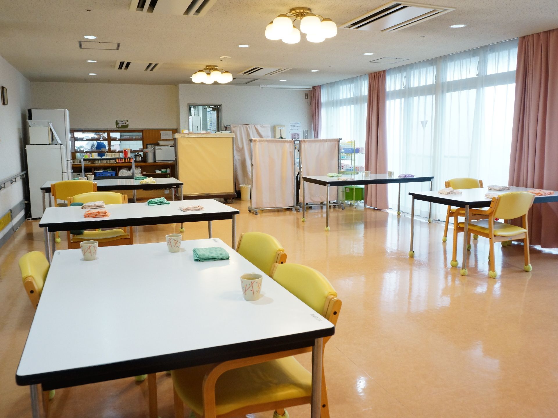 食堂は、テーブルが複数台置かれており、1脚から3脚程度の椅子が置かれている。奥には、カウンターが見える。
