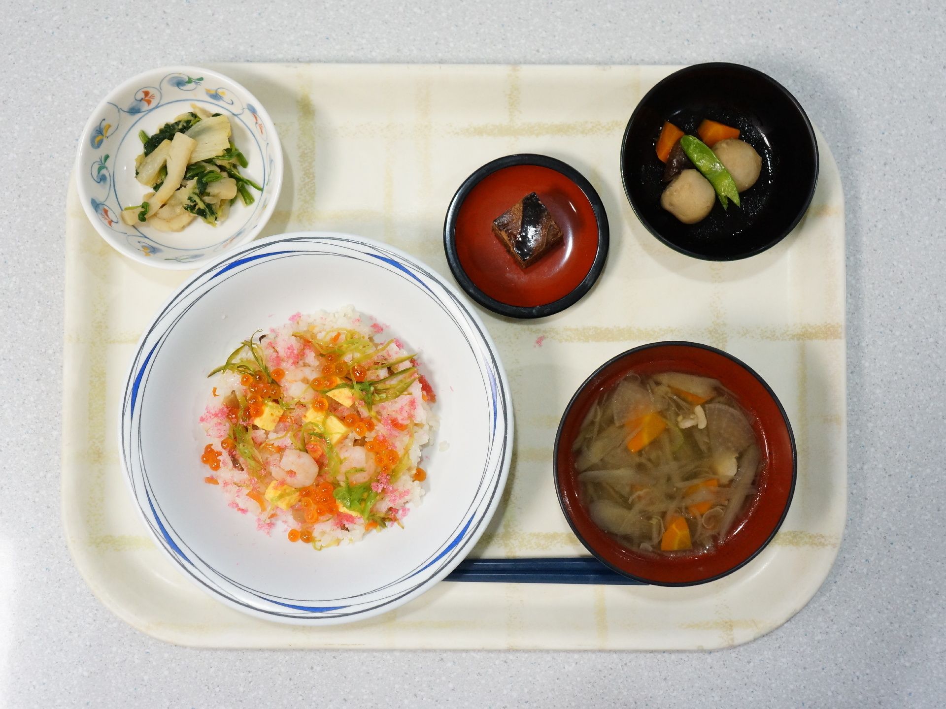 トレーの上に、ちらし寿司、汁物、煮物、副菜、デザート、箸が置かれている。ちらし寿司にはいくら、卵、桜でんぶなどが和えられ、彩りがきれい。