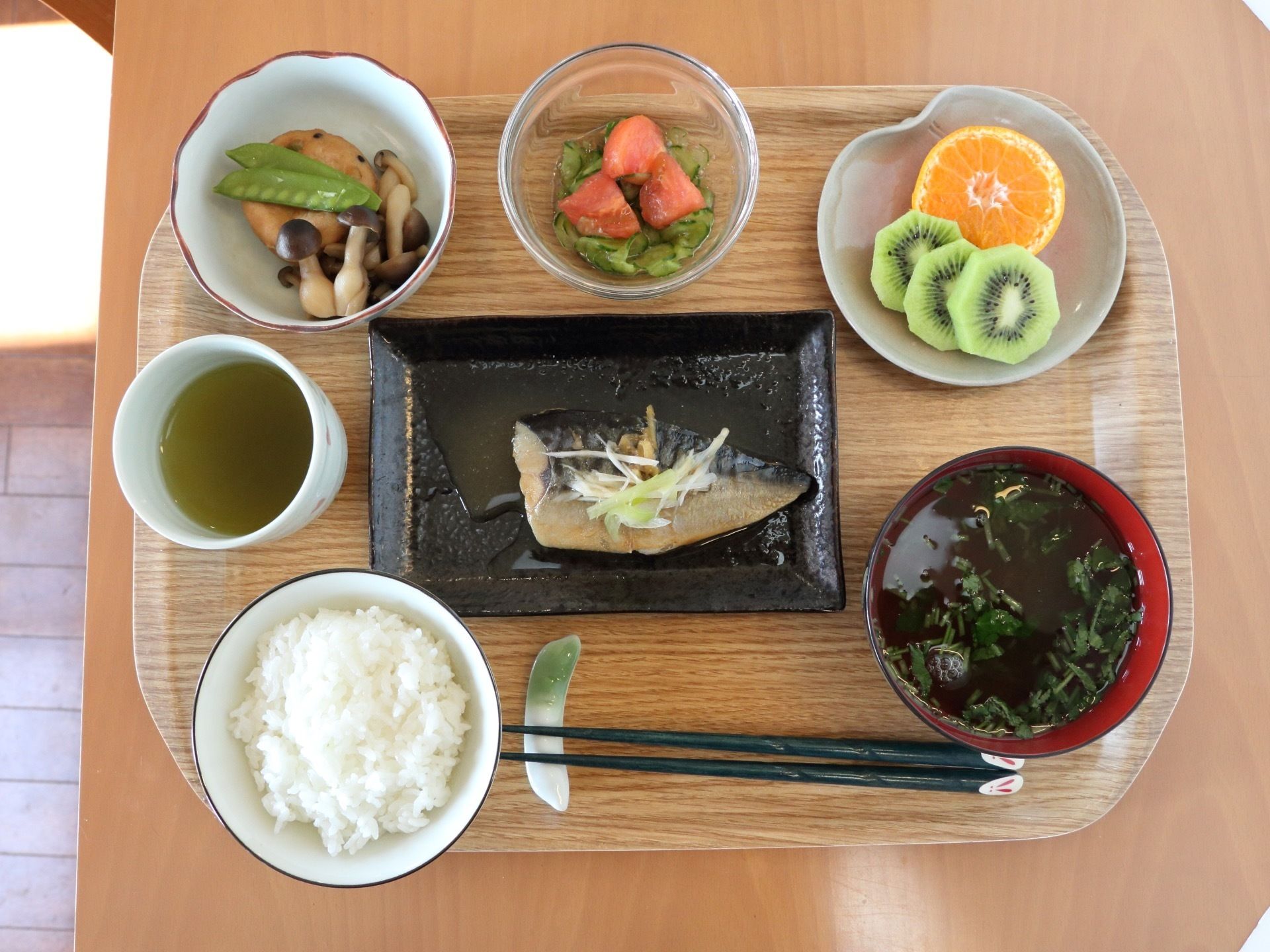 トレイの上に、中央に魚のメイン料理、手前にご飯と汁物、そして、小鉢を３品添えて並べている。彩りがキレイな食事である。